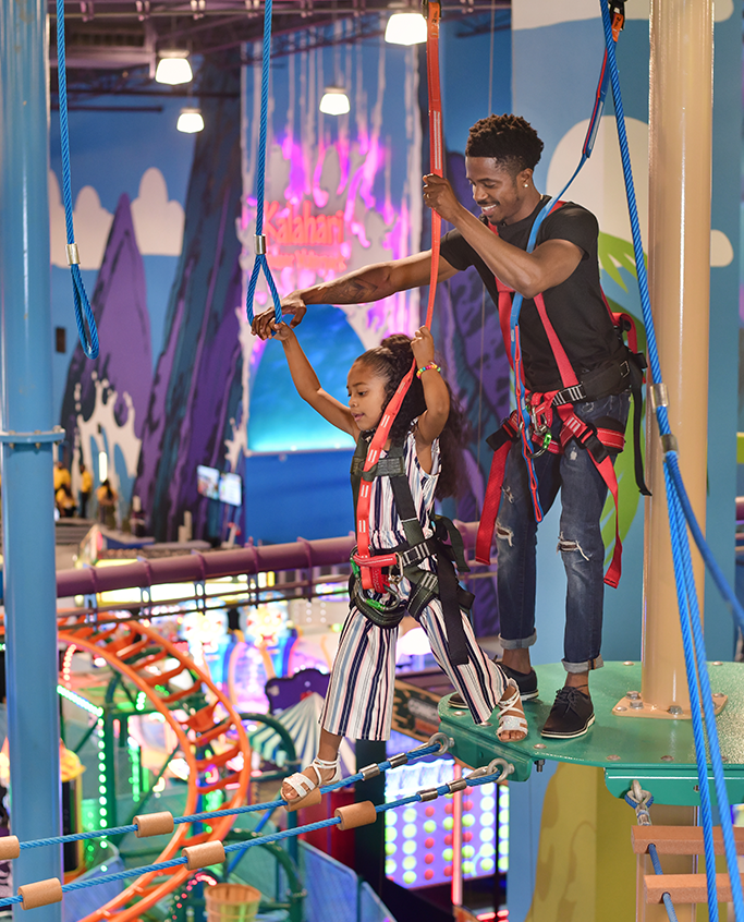 Girl going on a ropes course with assistance from man